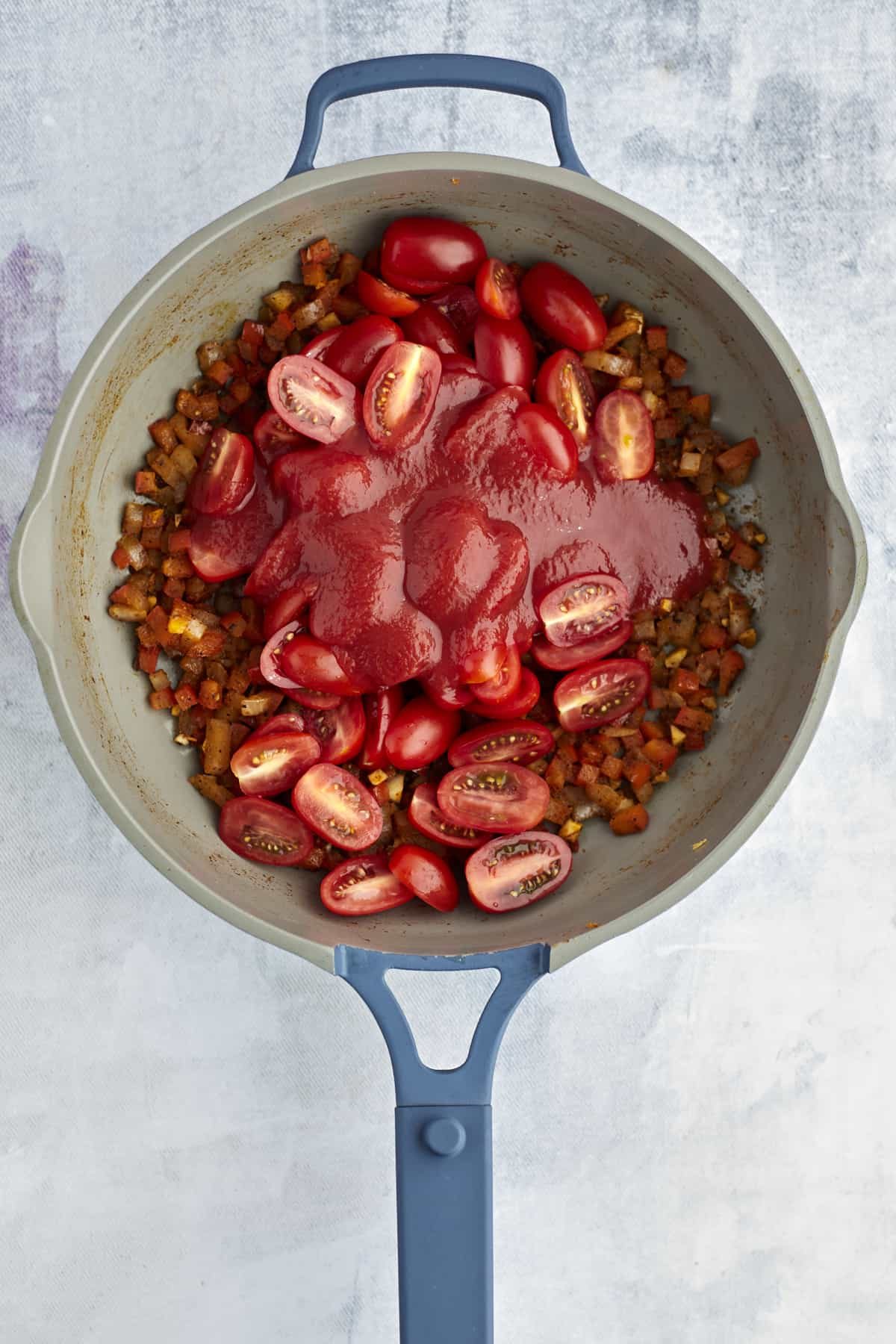 onions and peppers in a pot with halved tomatoes and tomato sauce
