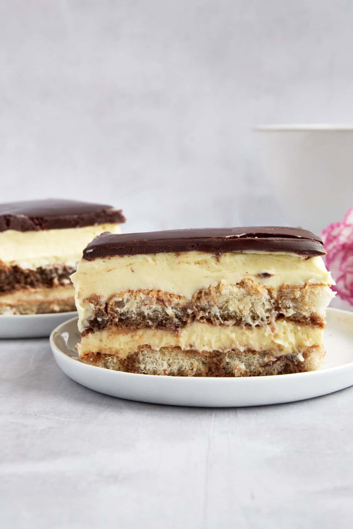 Two plates with slices of tiramisu eclair cake.