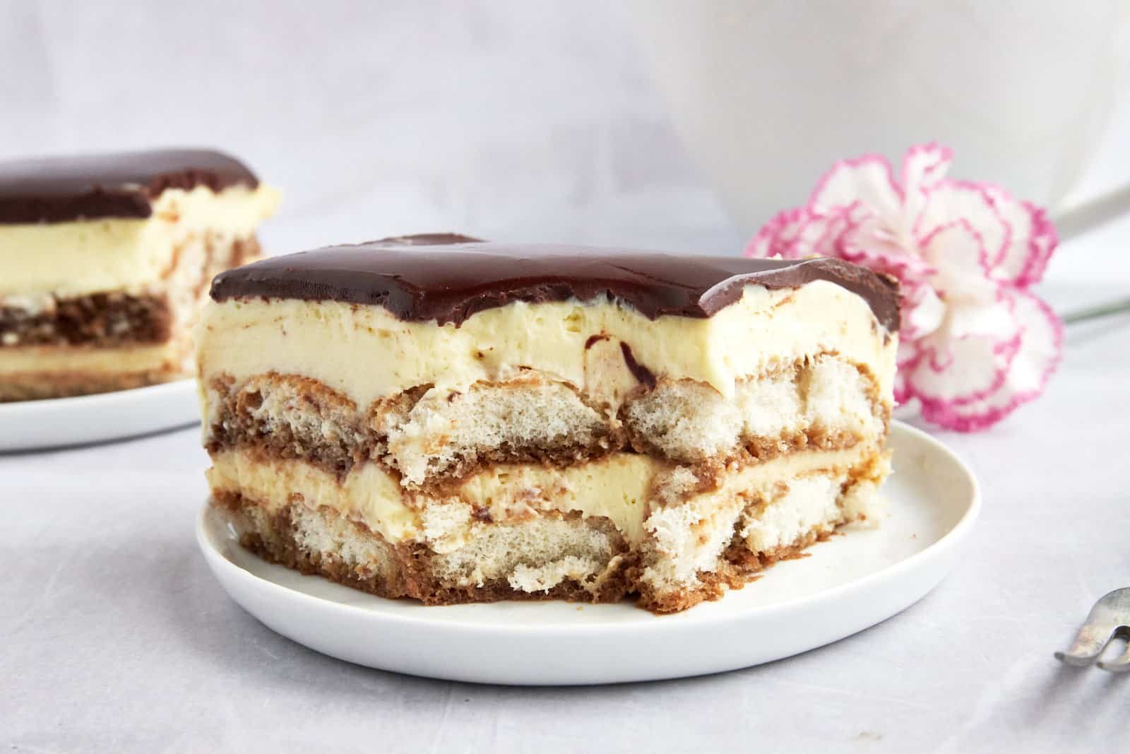 Tiramisu eclair cake on a plate missing a bite.