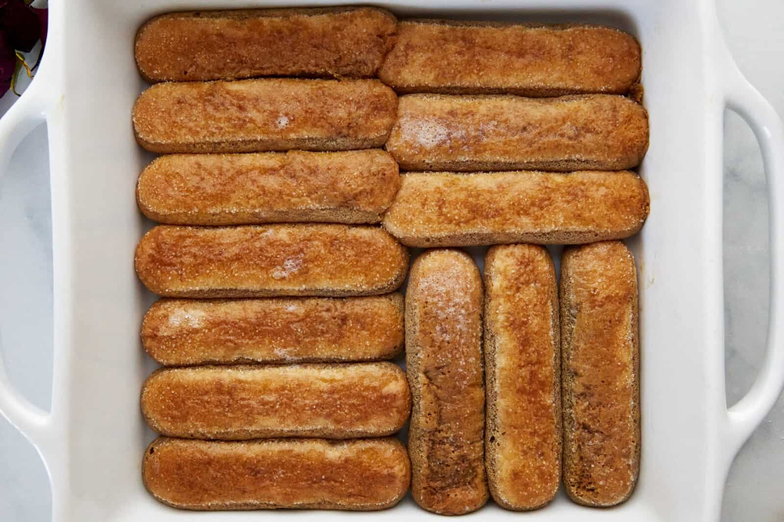 Coffee soaked ladyfingers in the bottom of a baking dish.