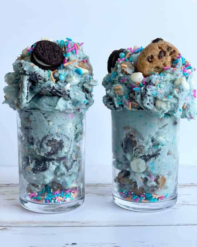 two jars of edible cookie monster cookie dough topped with Oreos and chocolate chip cookies