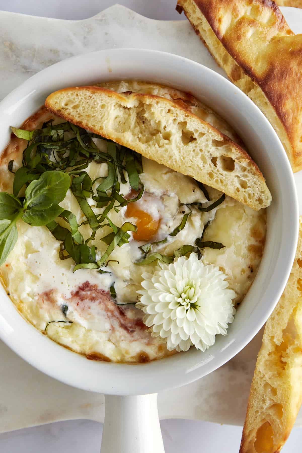 A ramekin of Eggs in Purgatory with a piece of bread on top.