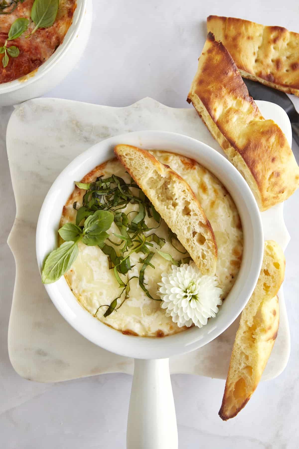 A ramekin of Italian baked eggs with pieces of bread on the side.