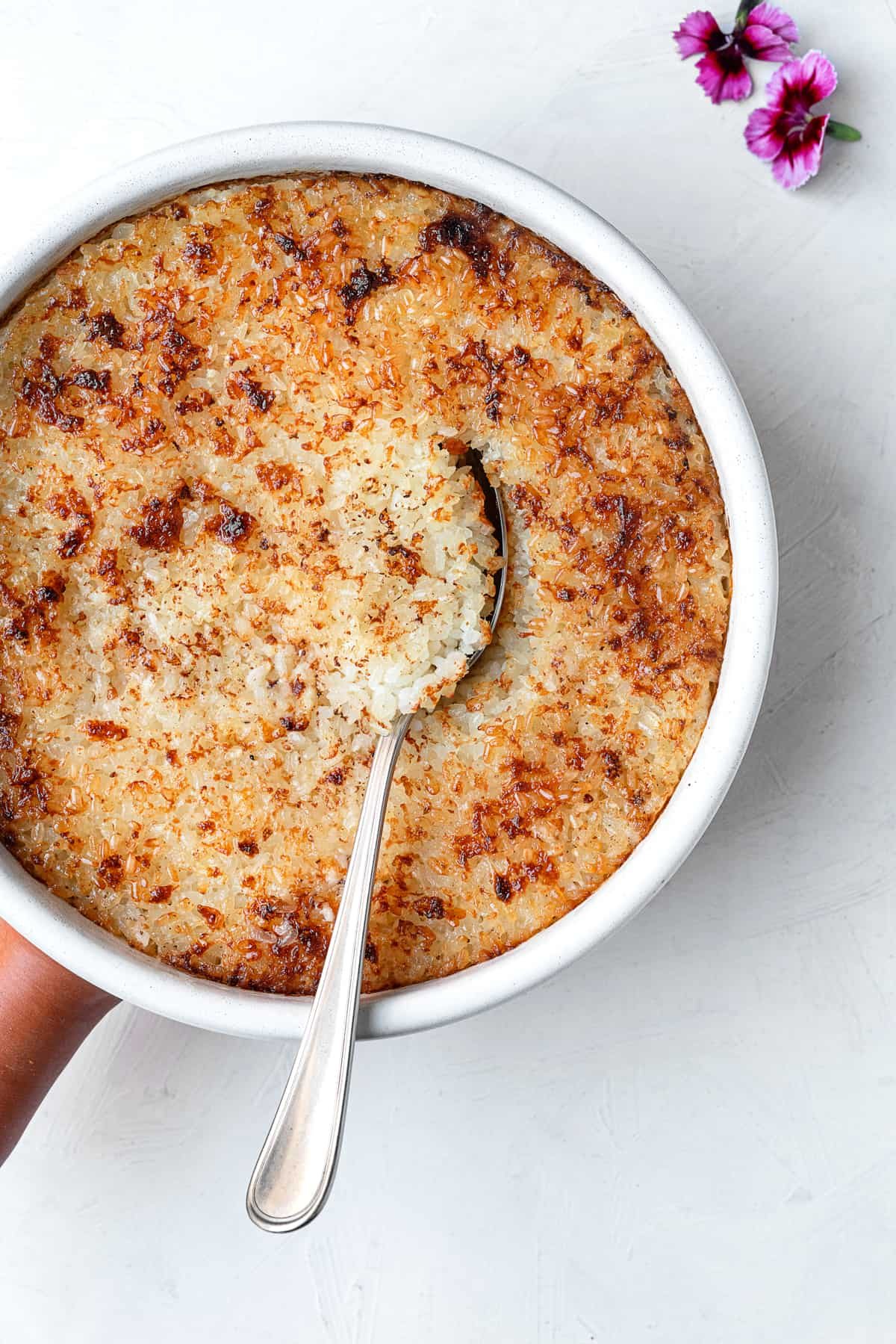 a bowl of Egyptian baked rice with a spoon dug in