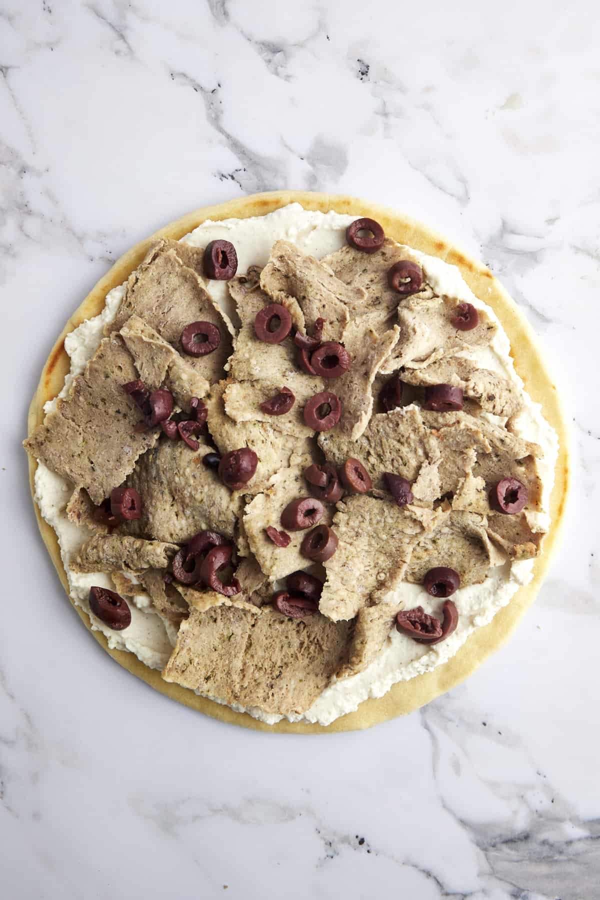 Pizza crust topped with whipped feta, gyro meat, and olives.