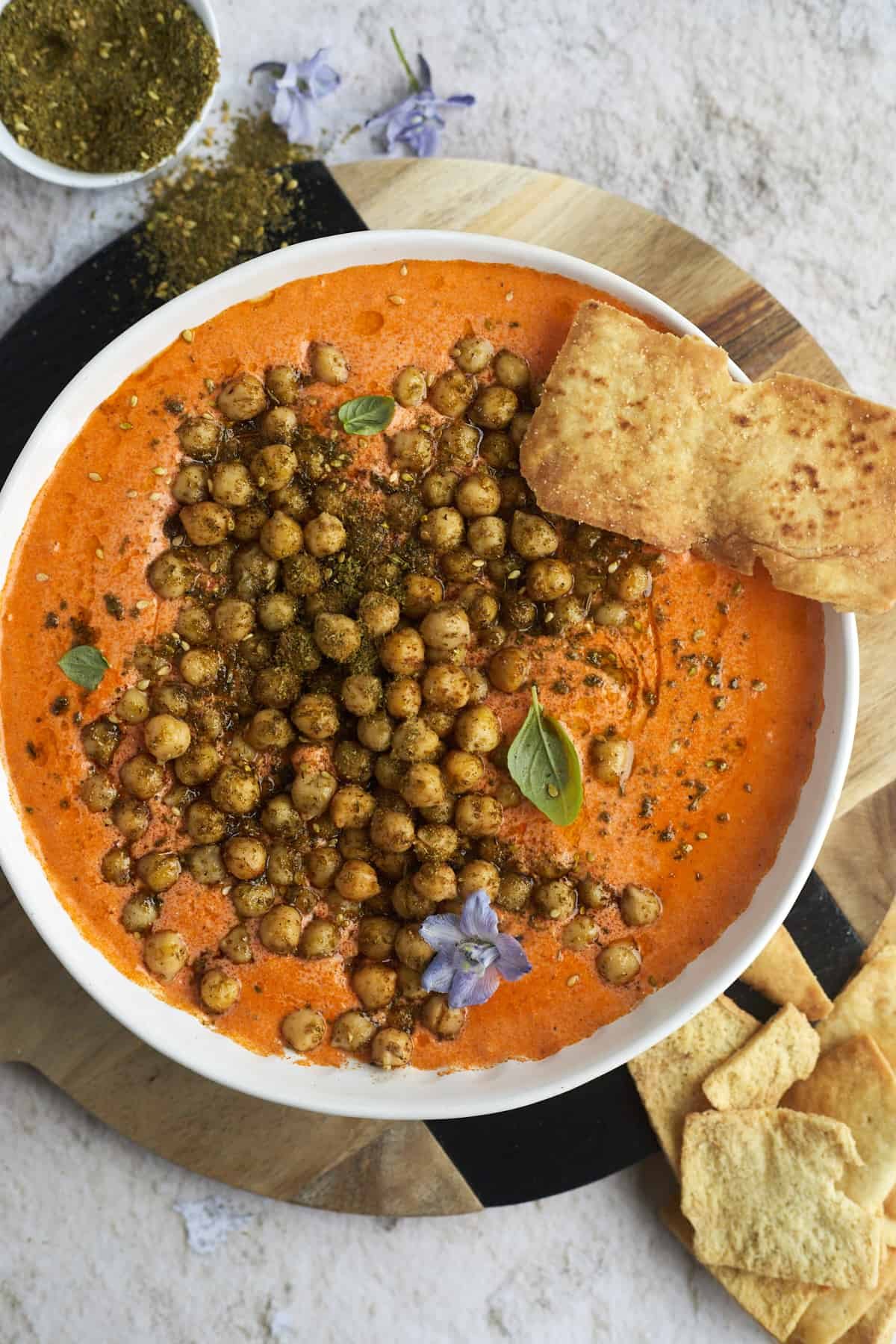 a bowl of Roasted Red Pepper Feta Dip with Crackly Chickpeas with crackly pita chips on the side
