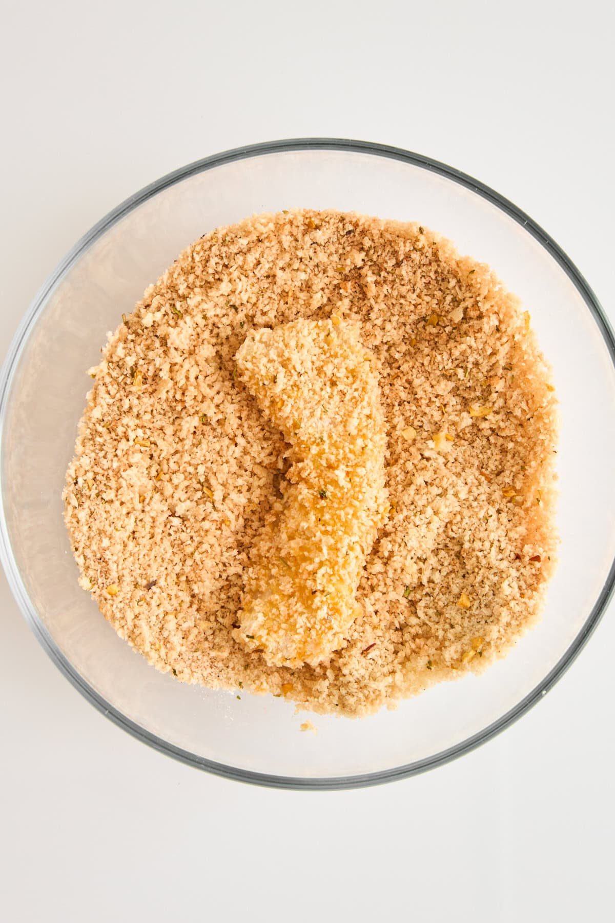 A cod piece in a bowl of panko breadcrumbs.