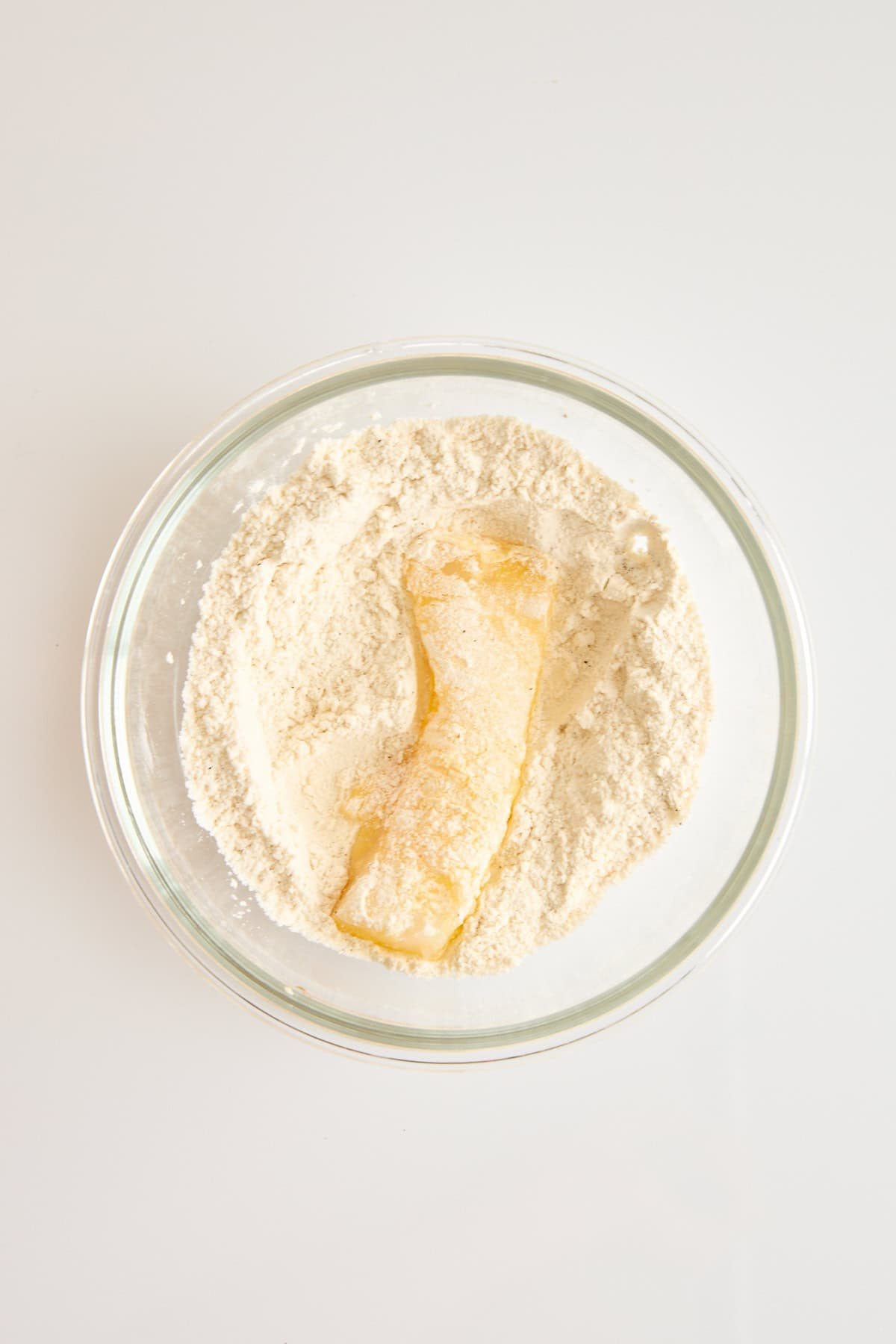 An egg dipped cod piece in a bowl of flour.