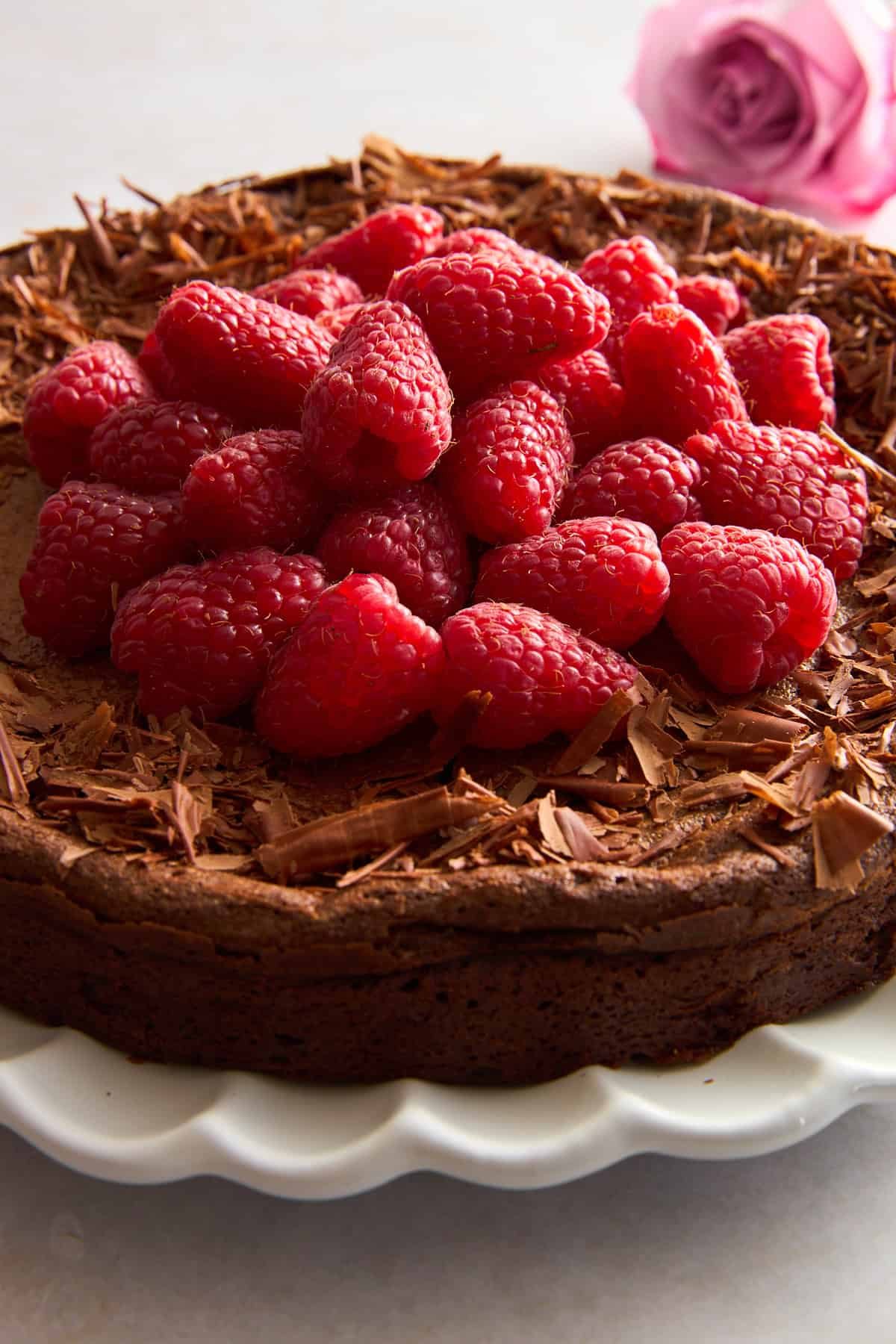 A flourless chocolate cake topped with chocolate shavings and raspberries.