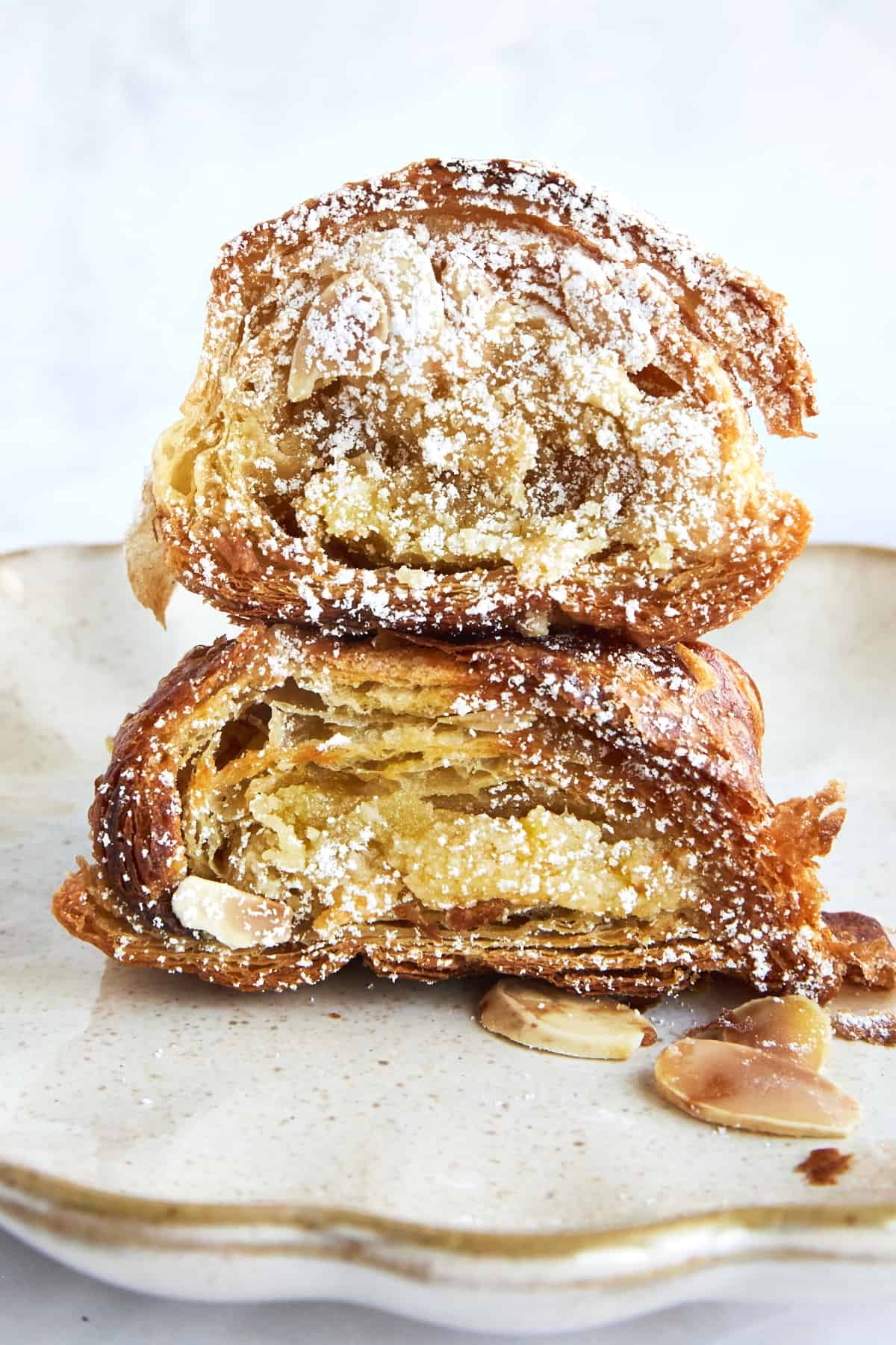 Two pieces of almond croissant French toast stacked on top of each other topped with powdered sugar.