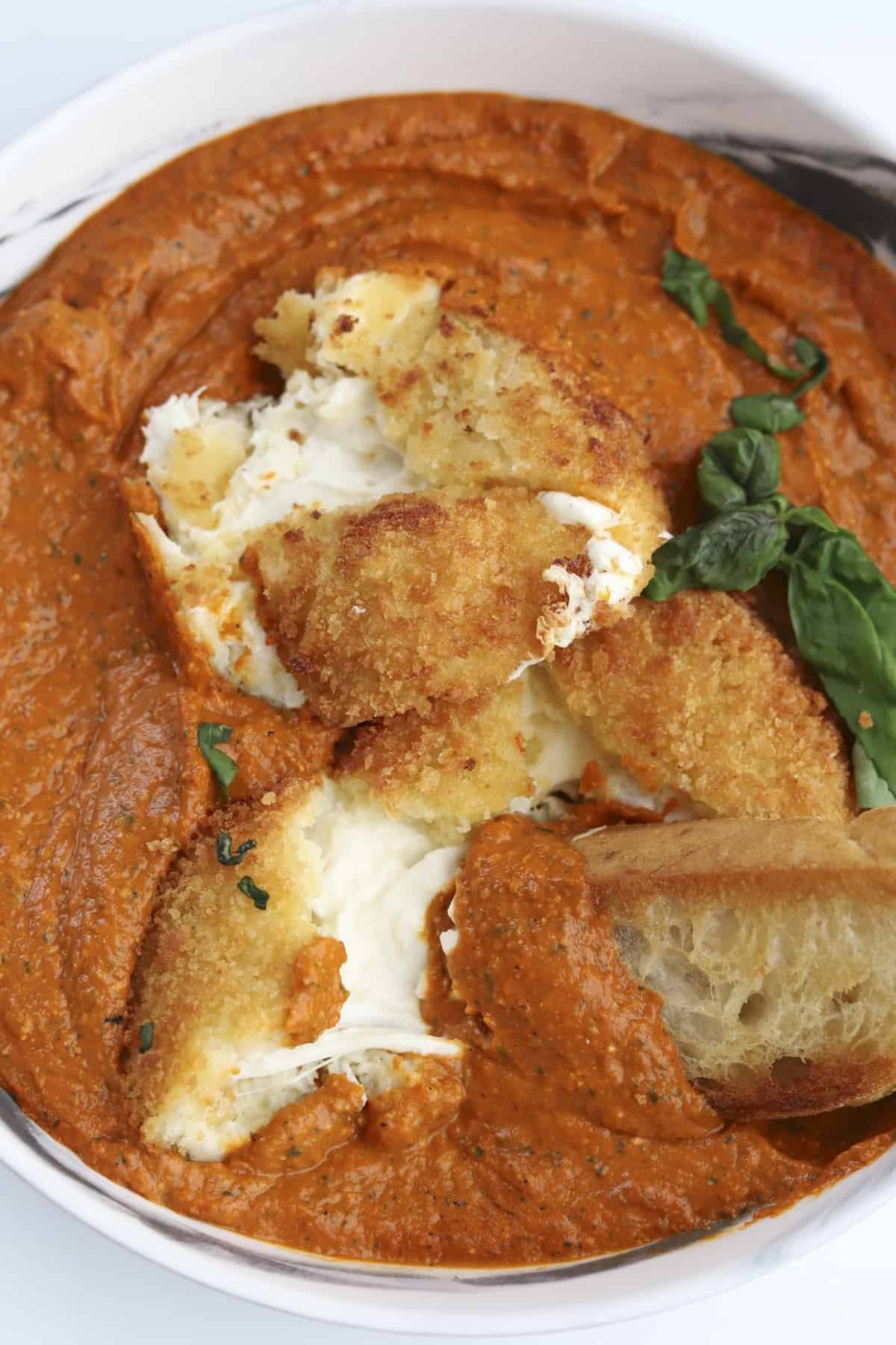 plated fried burrata cut open with romesco sauce and baguette