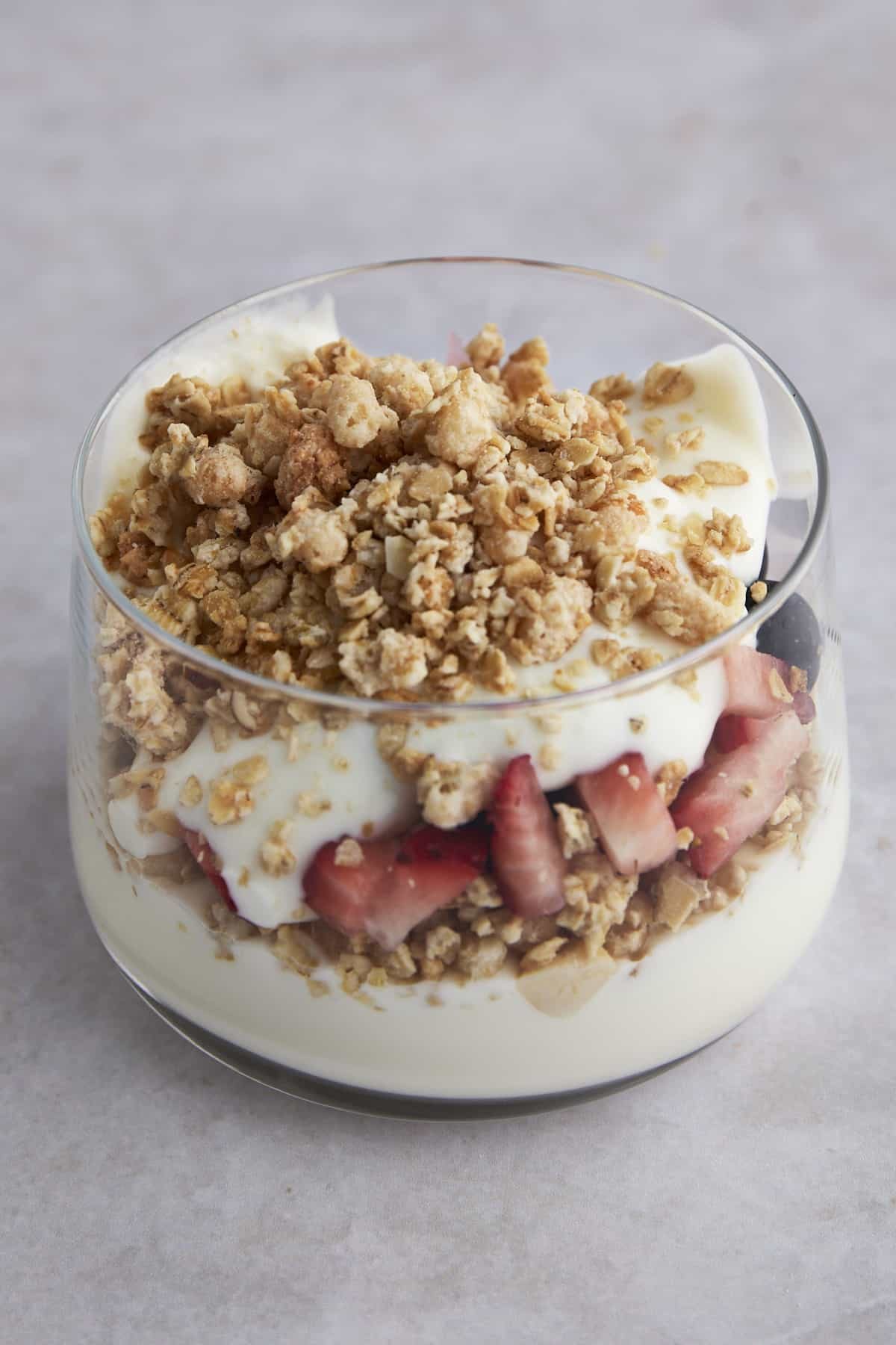 Side view of a fruit and yogurt parfait with yogurt, strawberries and granola.
