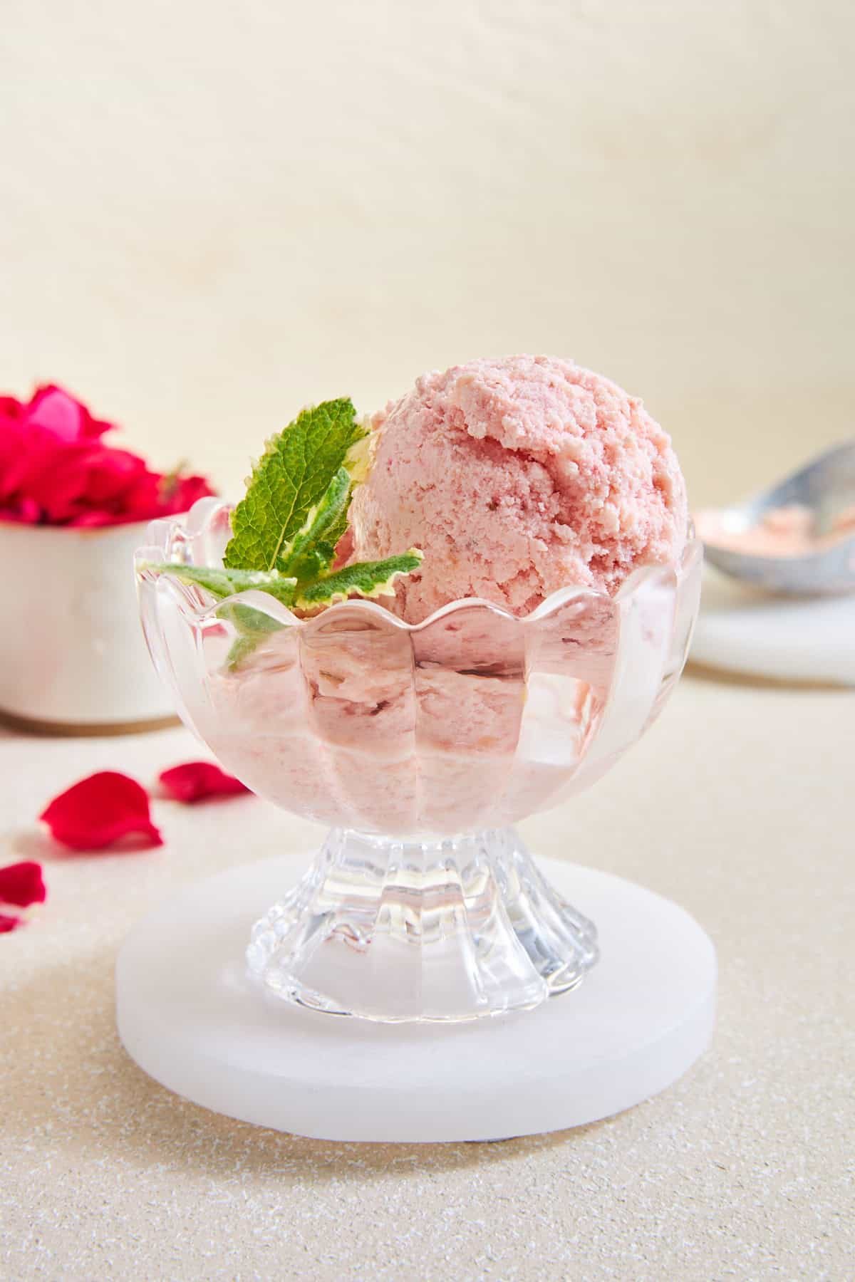 A glass serving cup of peach and strawberry fruit ice cream.