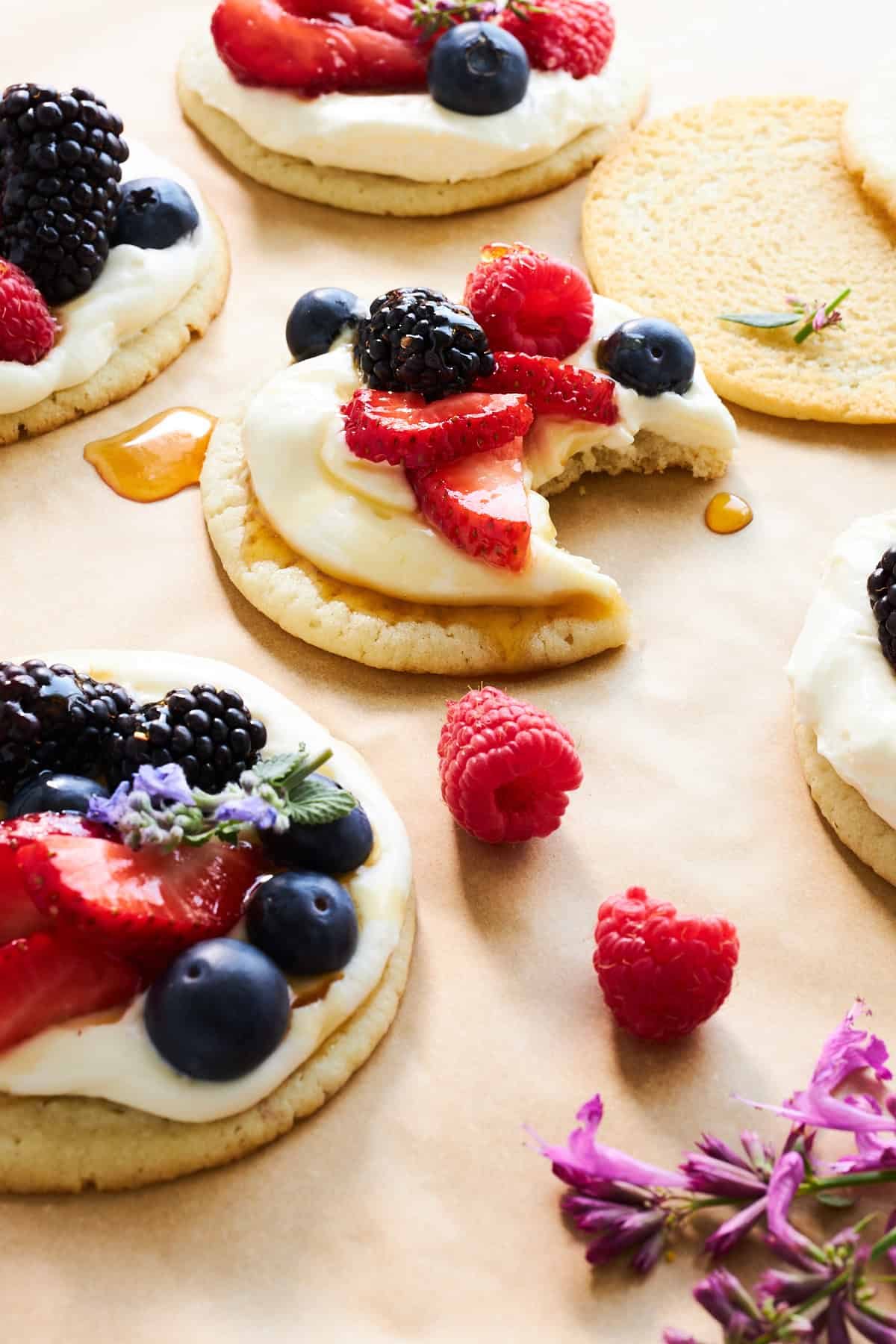 Fruit pizza cookies topped with berries with one missing a bite.