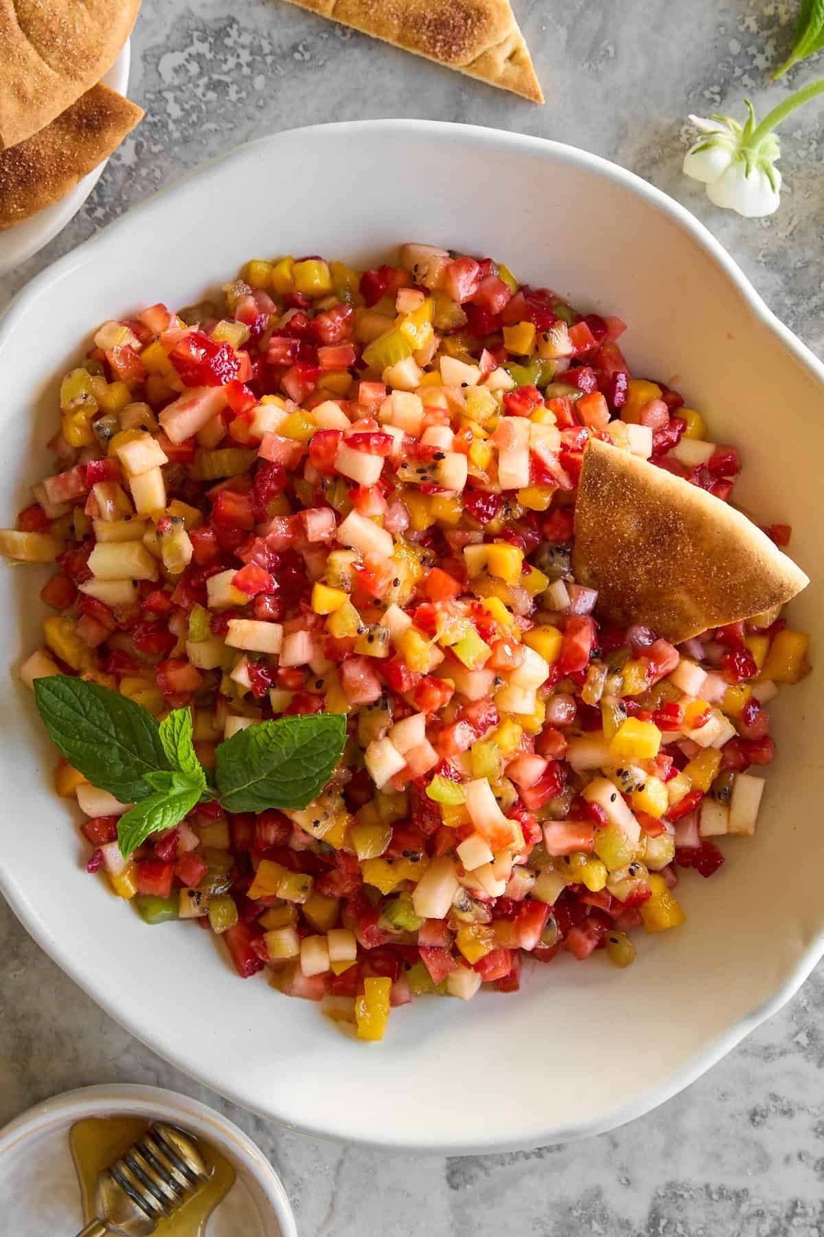 A bowl of fruit salsa with a pita chip sticking out.