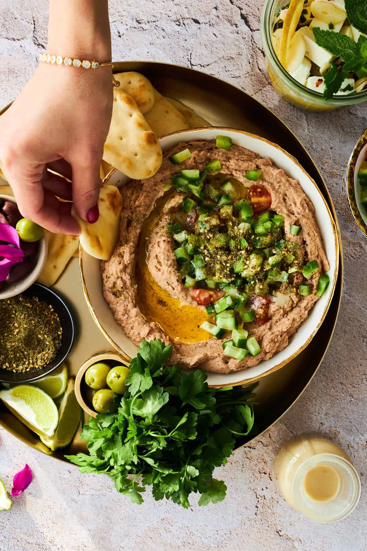 A hand dipping a pita chip into a bowl of ful medames.
