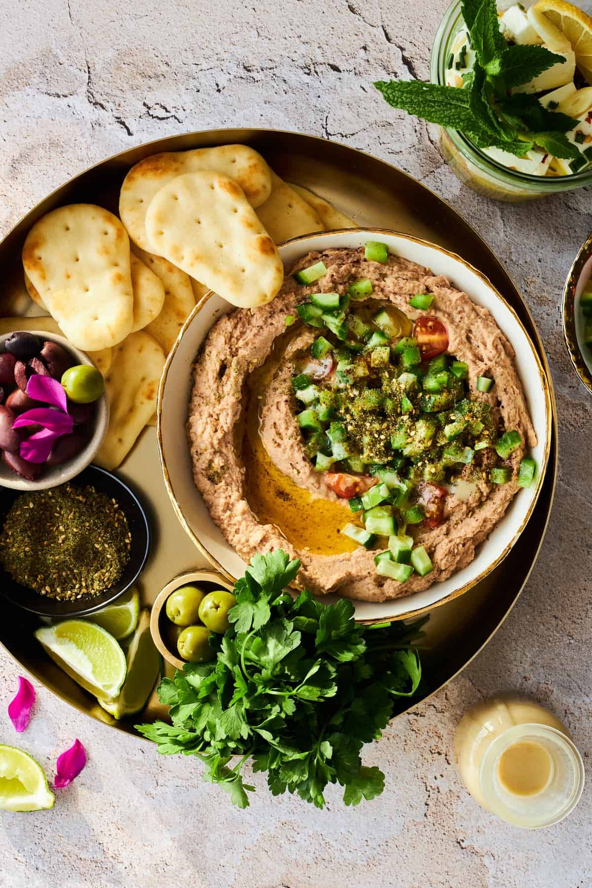 A bowl of ful medames on a platter with pita chips.