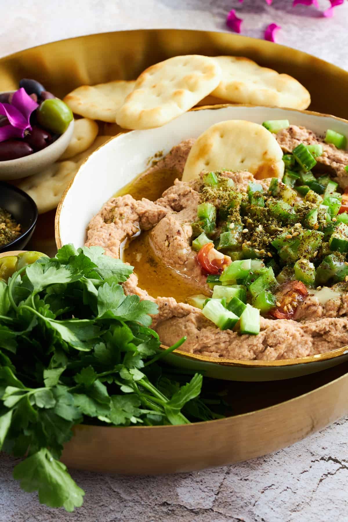 A bowl of Egyptian fava beans with pita chips sticking out.
