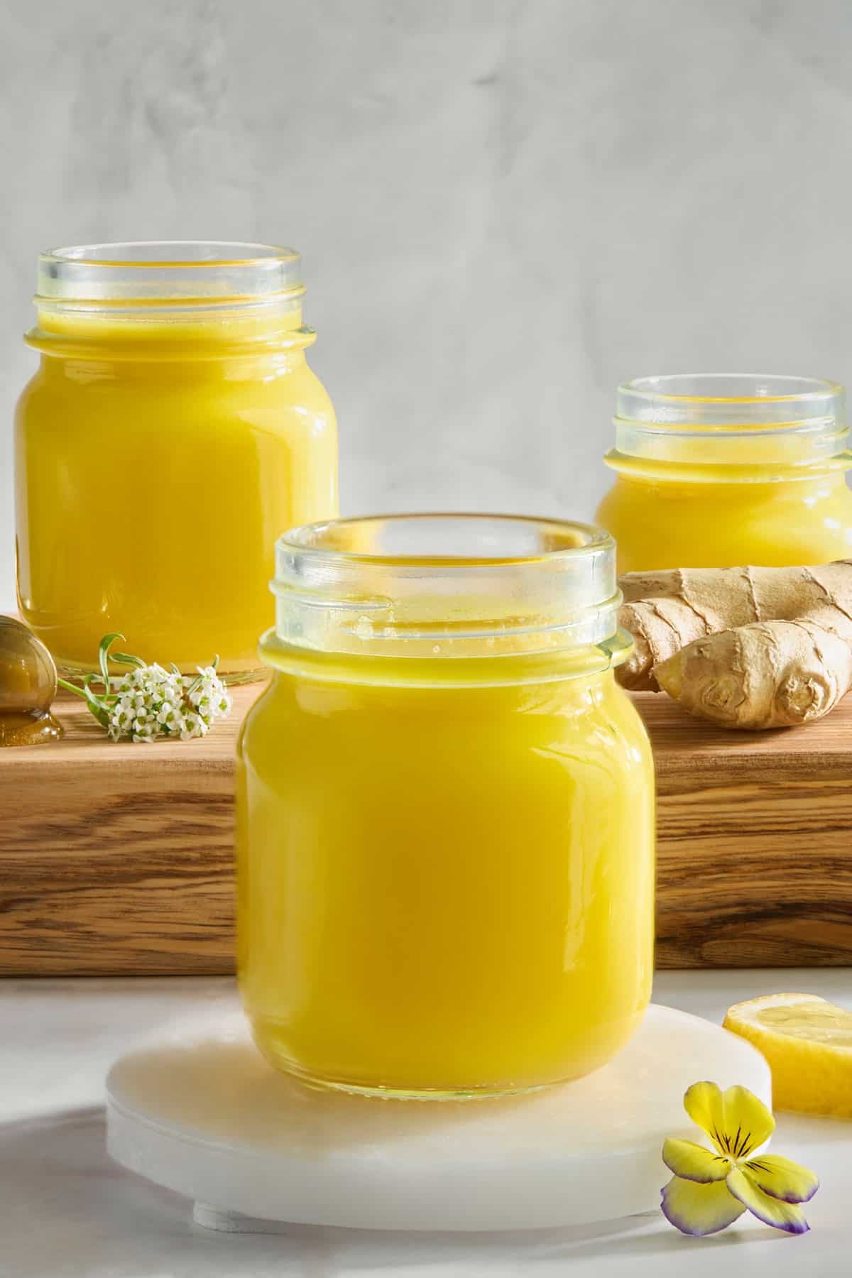 Three ginger and turmeric shots in glass jars.