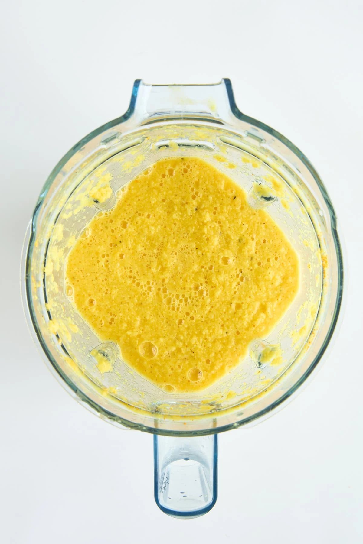 Overhead image of a ginger turmeric shots mixture in a blender.