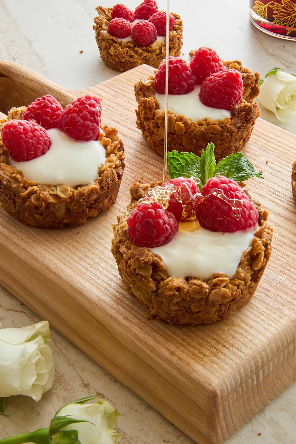 Yogurt Filled Granola Cups topped with raspberries and honey.