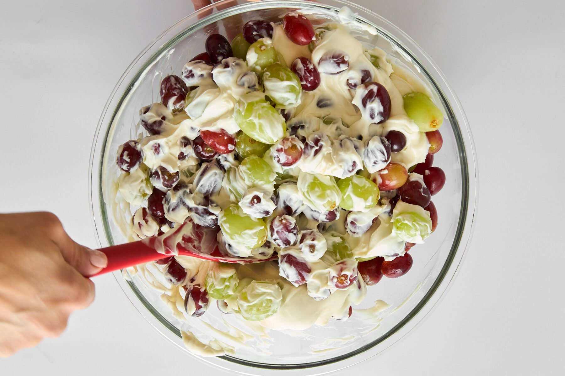 Grape salad being mixed in a bowl.