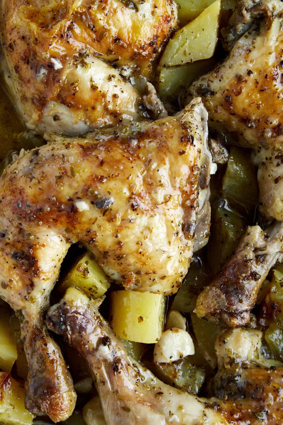 Close up view of baked lemon Greek chicken and potatoes.