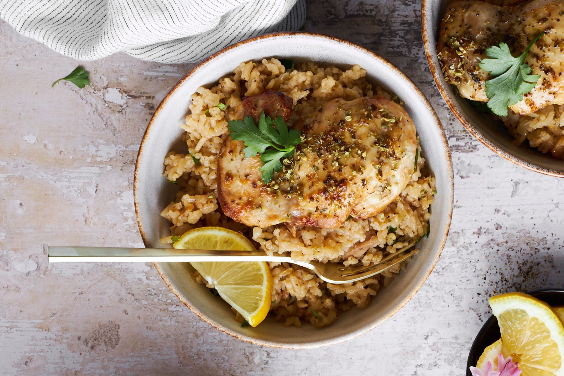 A bowl of Greek chicken and rice with a fork.