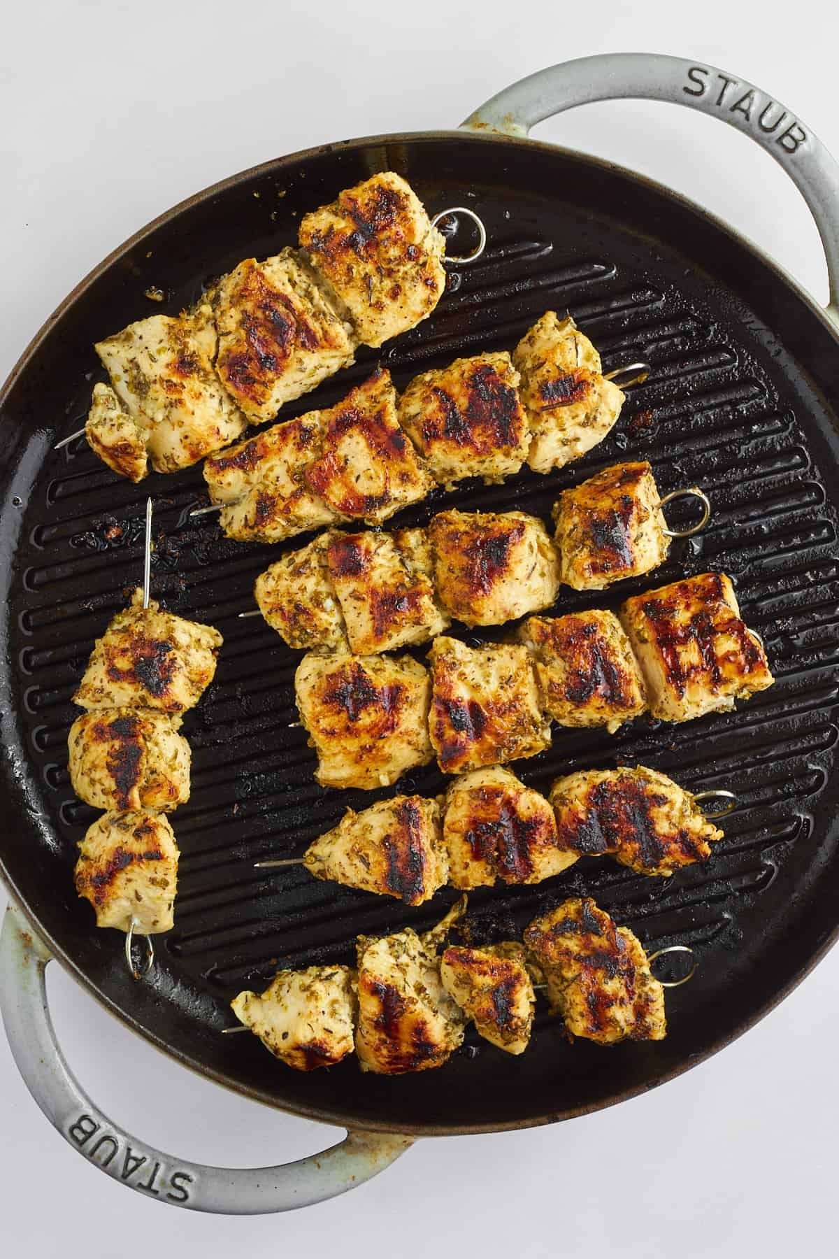 Grilled chicken souvlaki skewers on a grill pan.