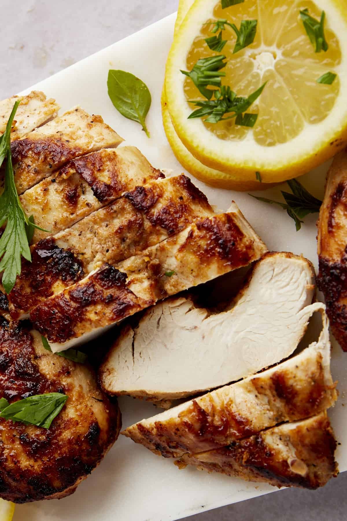 Sliced Greek lemon chicken on a cutting board.