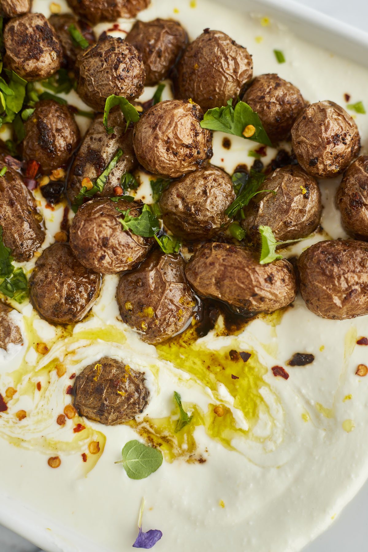 roasted potatoes on top of feta dip topped with red pepper flakes and oil