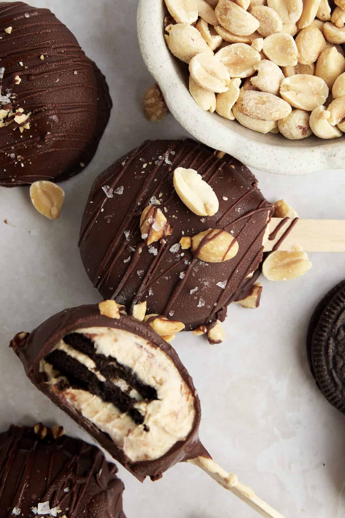 Peanut butter Oreo yogurt popsicles with a bite missing from one exposing the Oreo center.