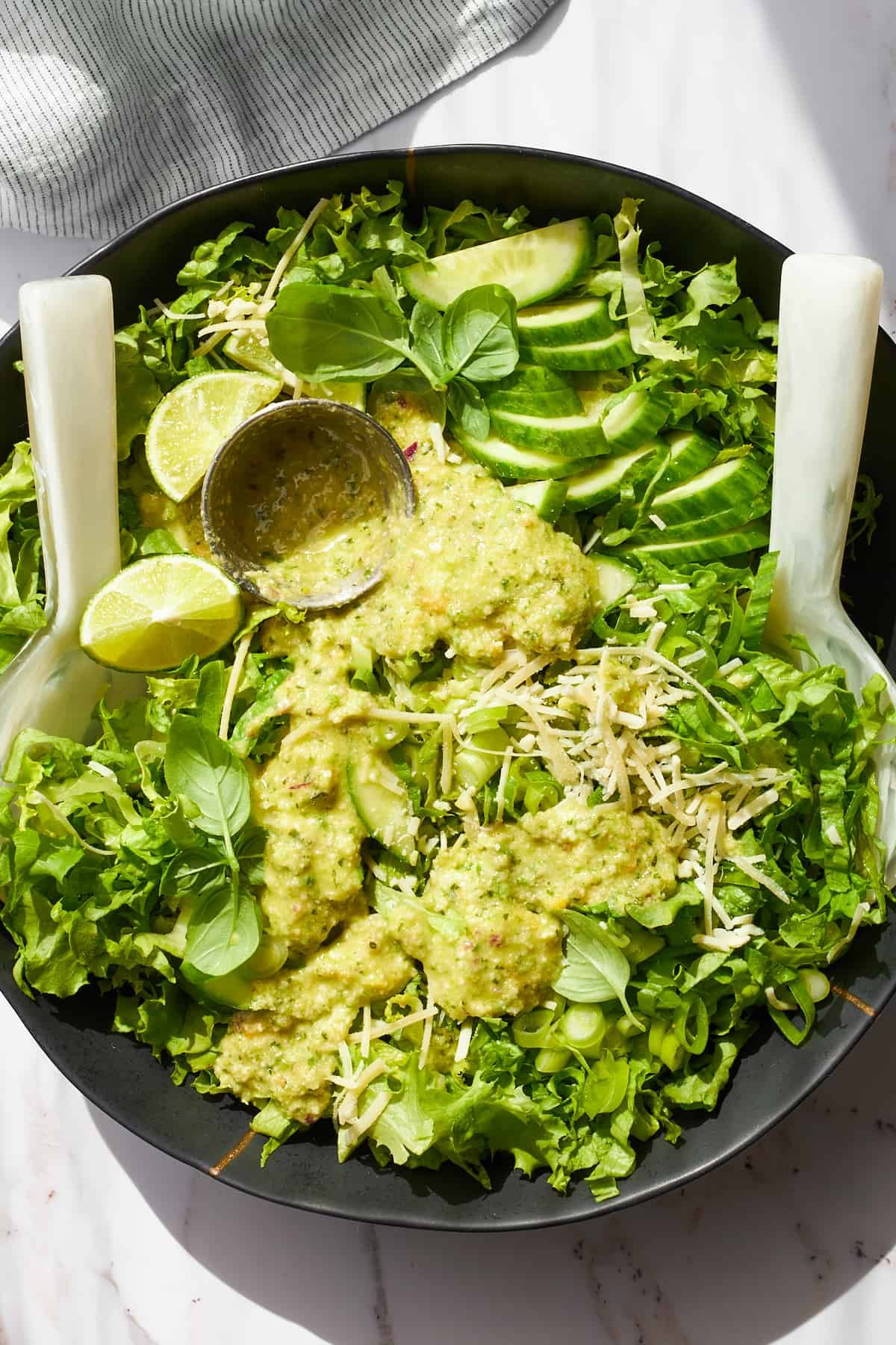 A bowl of green goddess salad with green goddess dressing on top.