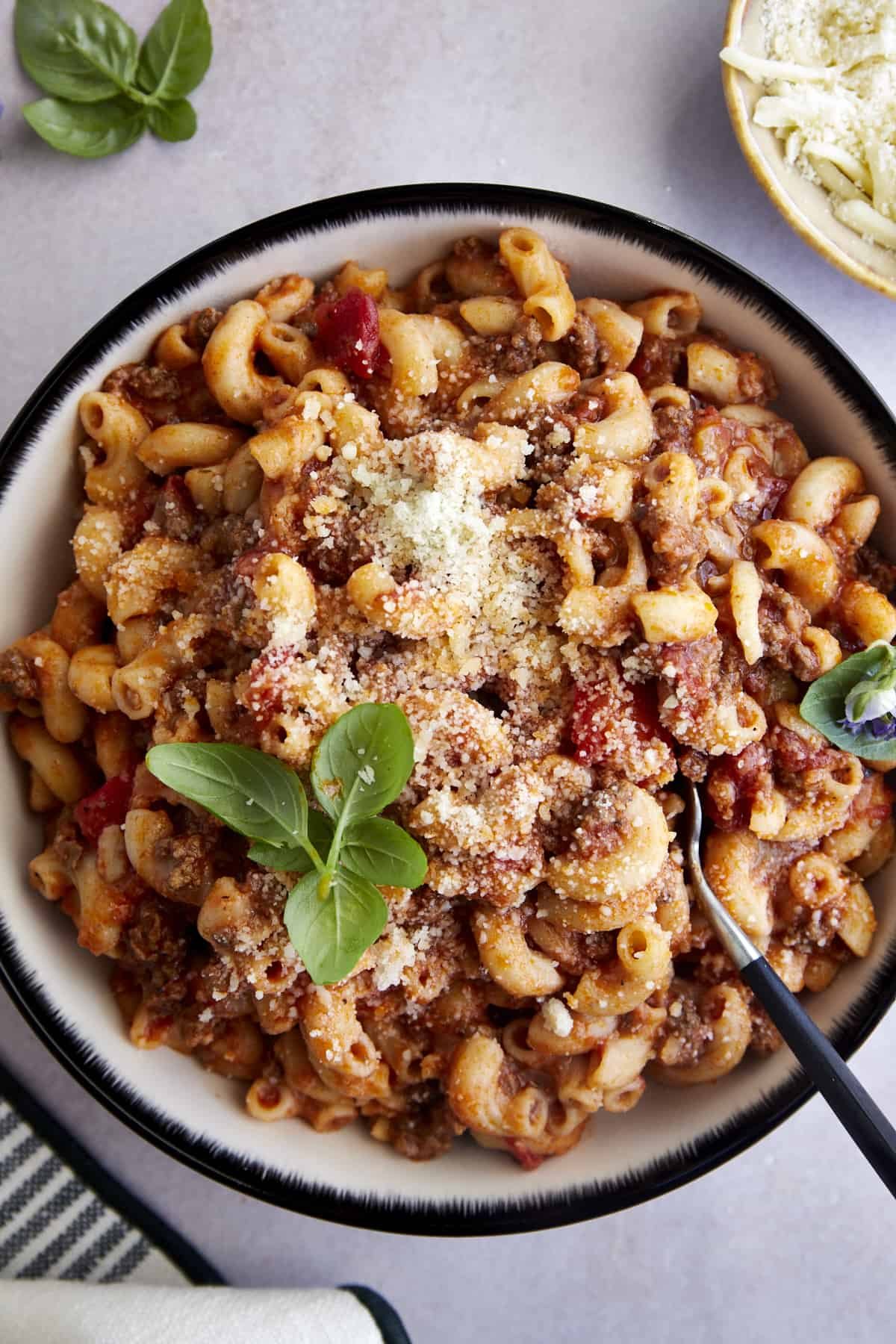 A bowl of ground beef pasta topped with Parmesan and fresh parsley.