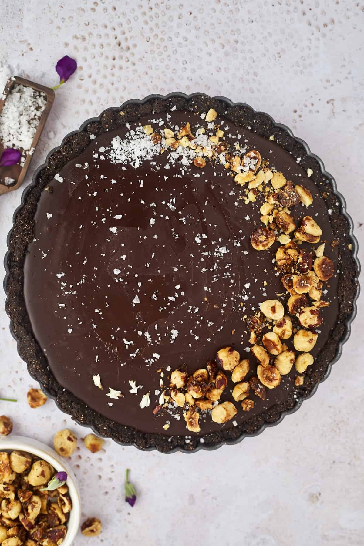 A whole chocolate tart topped with candied hazelnuts and sea salt.