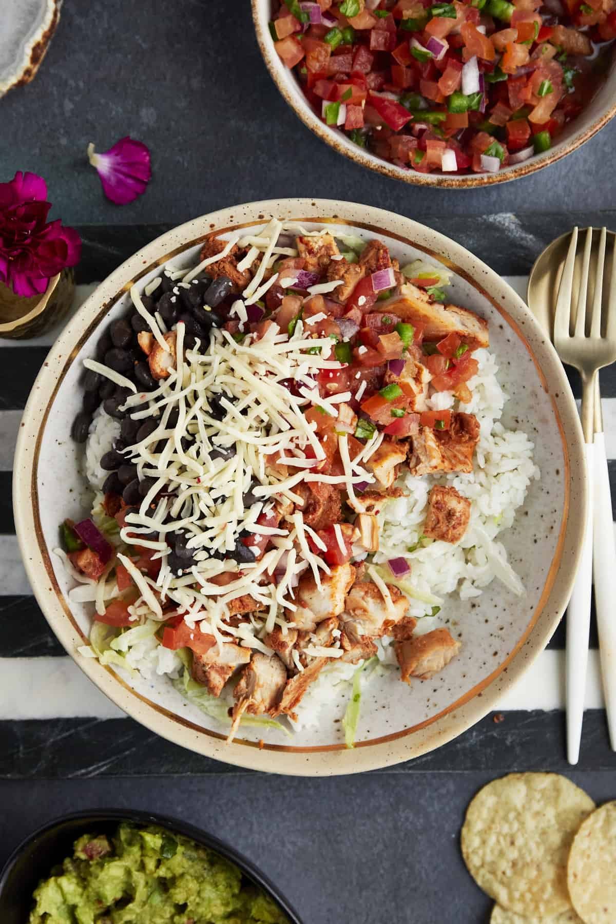 a from-scratch chipotle bowl with rice, chicken, lettuce, salsa, black beans, and cheese