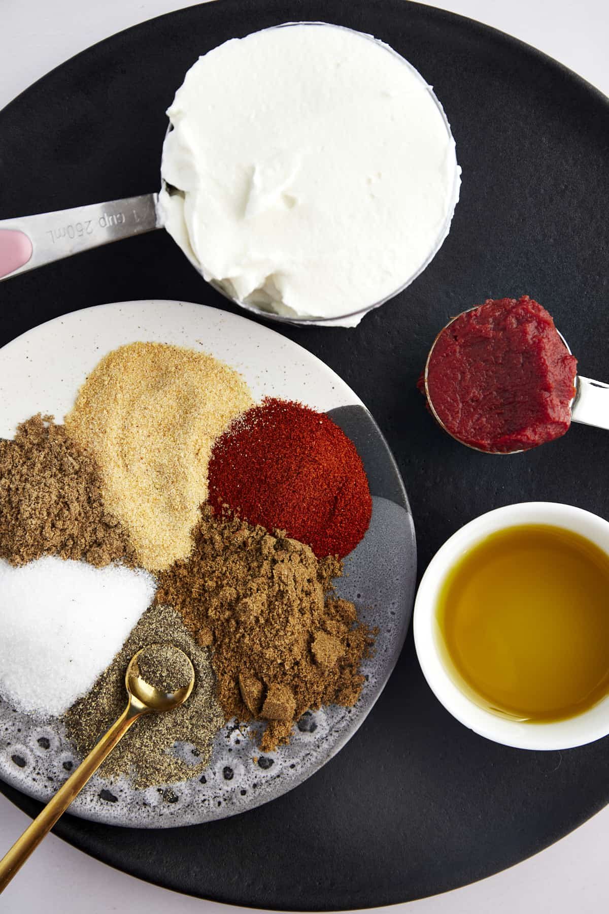 Seasonings, yogurt, tomato paste, and olive oil prepared to make a whole chicken.