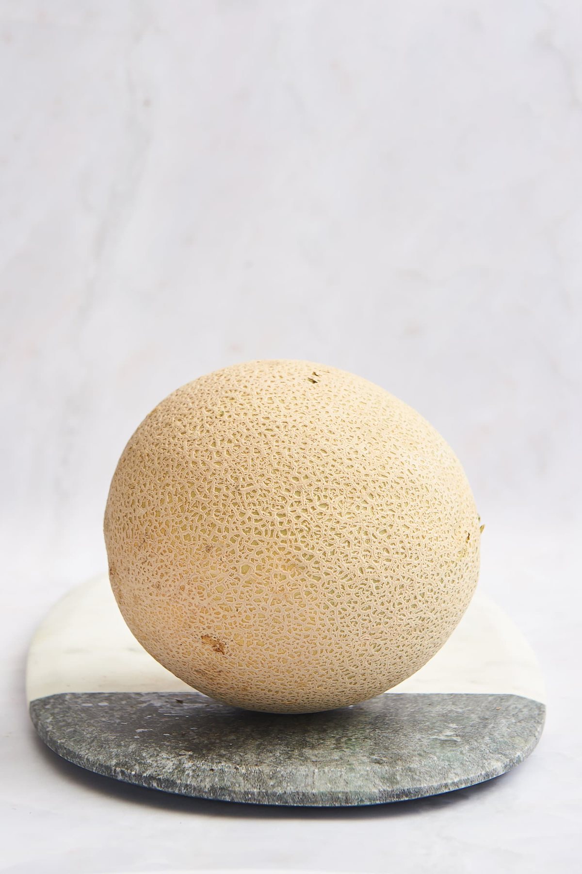 A melon on a cutting board.
