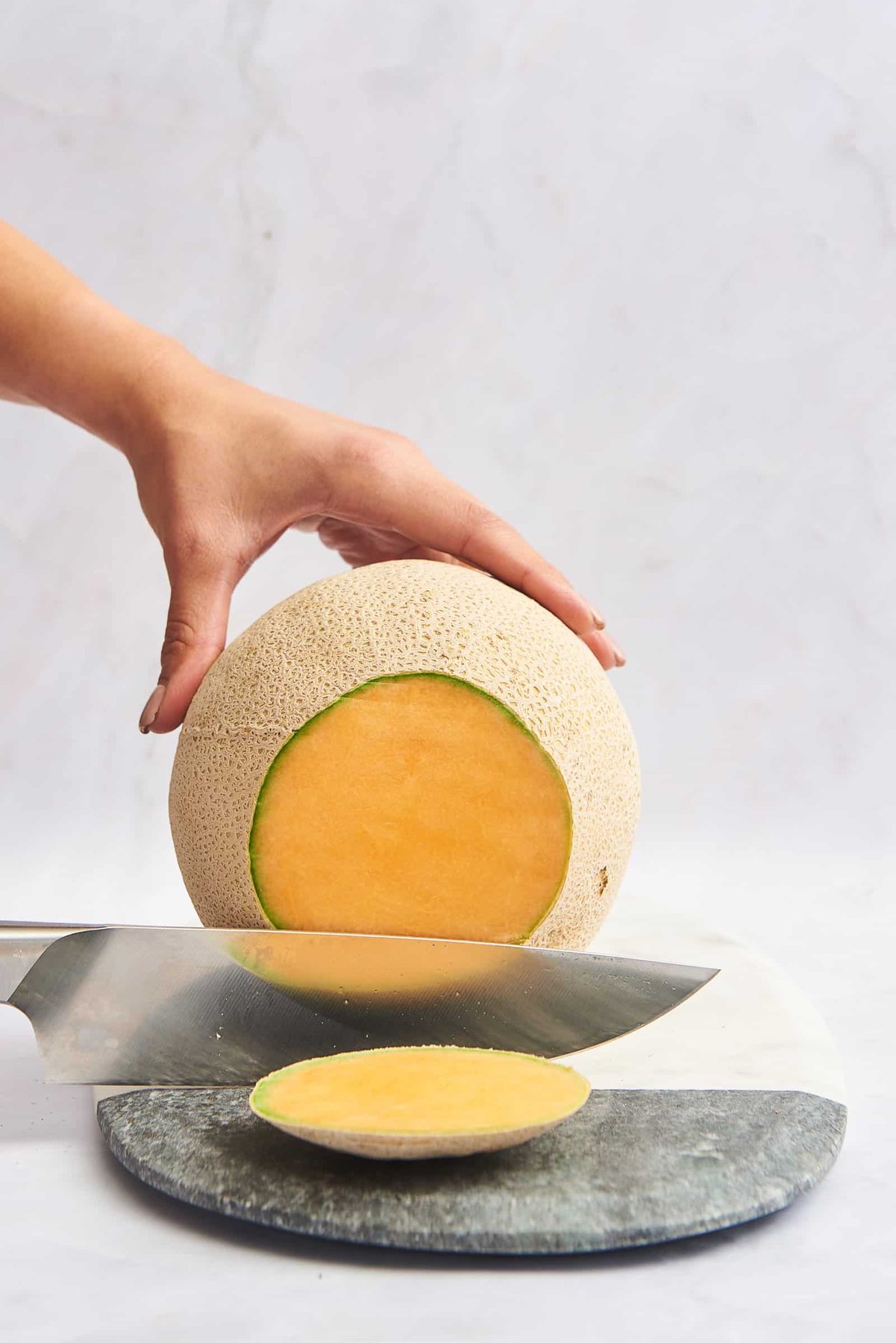 The end being trimmed off a cantaloupe.