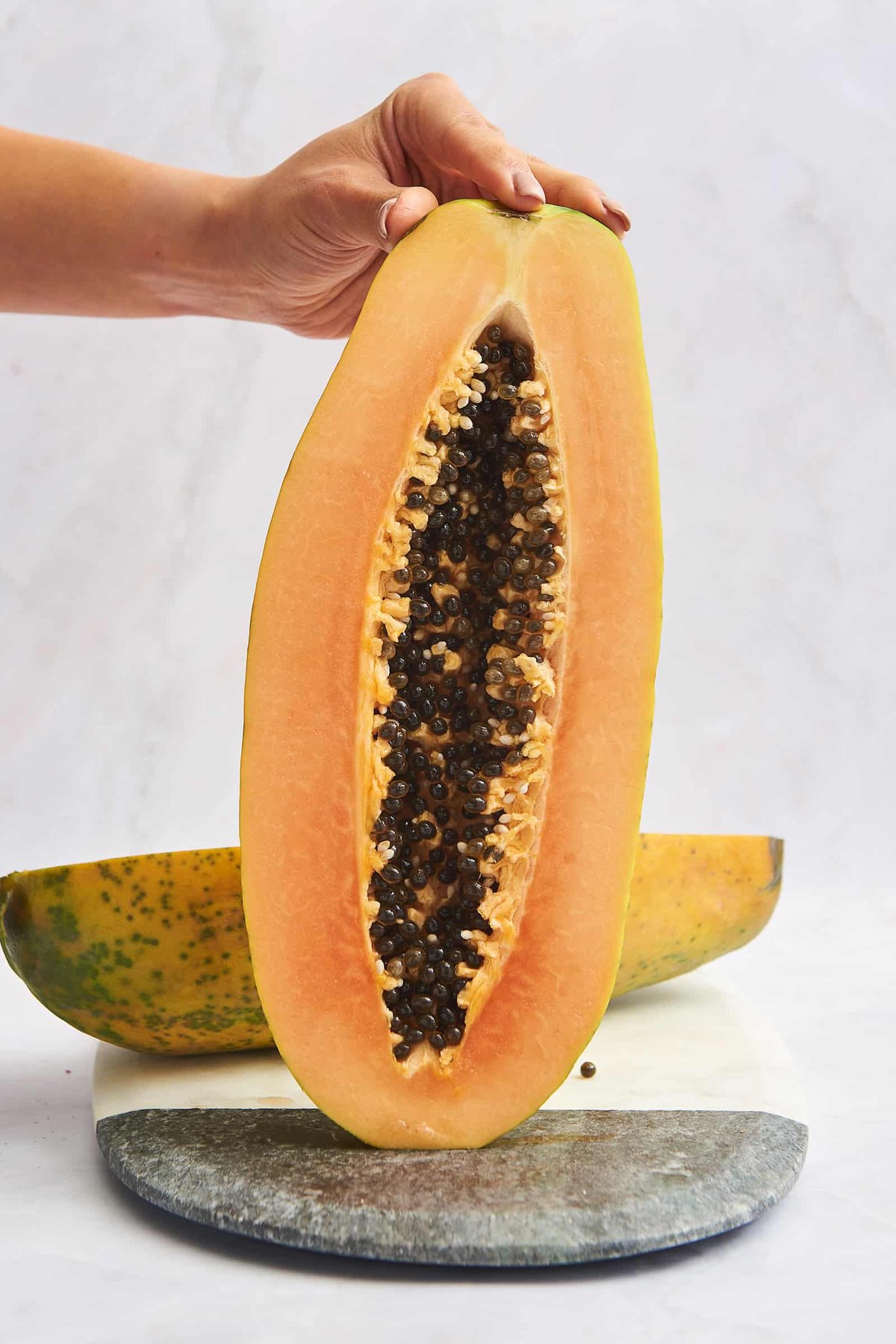 A hand holding a halved papaya.