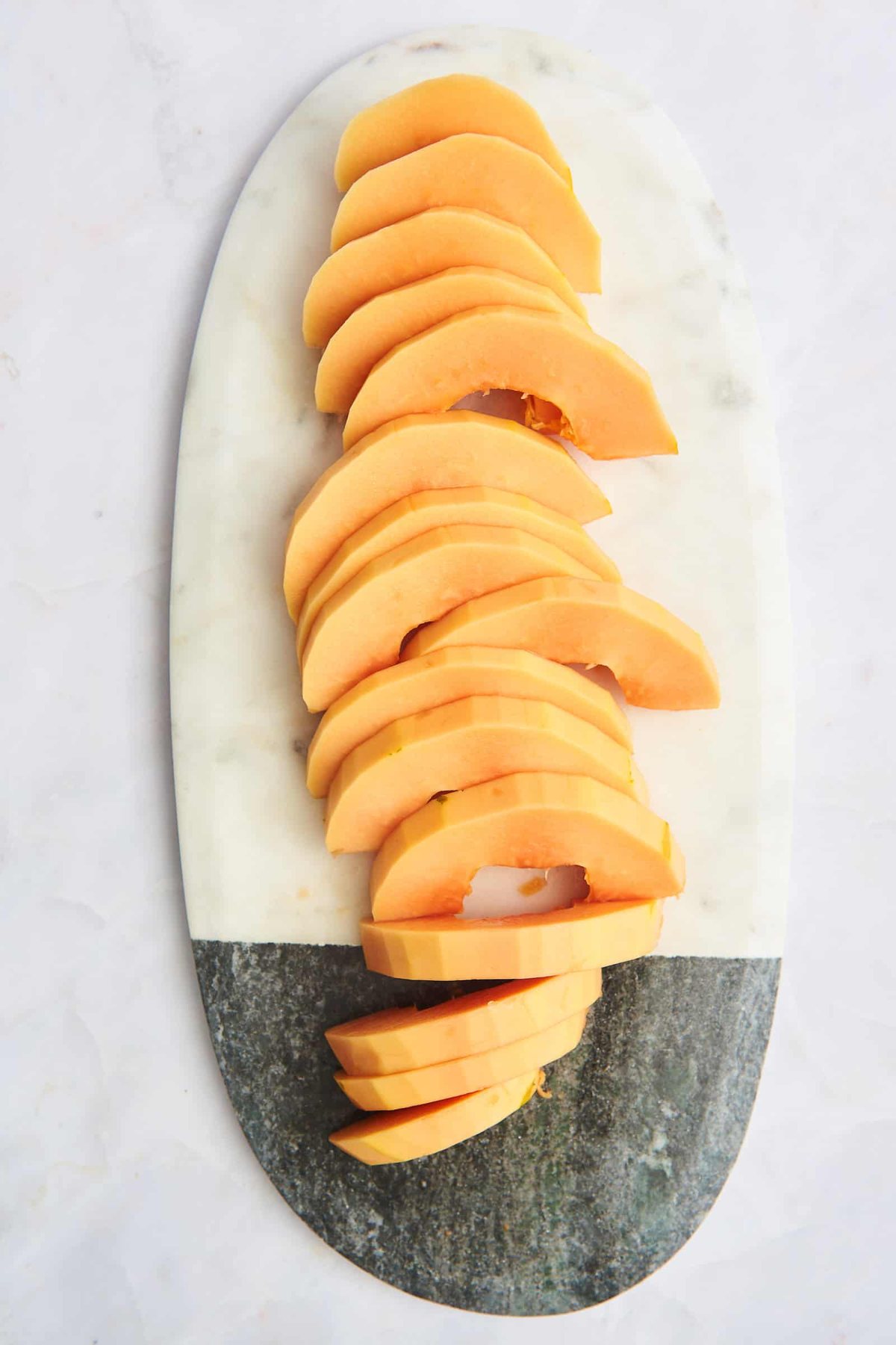 Half moon pieces of papaya on a cutting board.