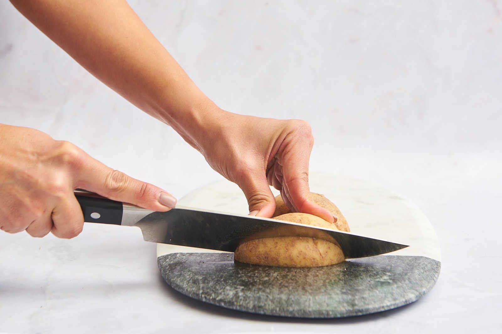 A potato being cut into wedges.
