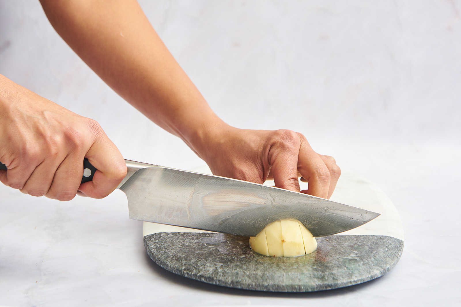 A peeled potato being cut into cubes.