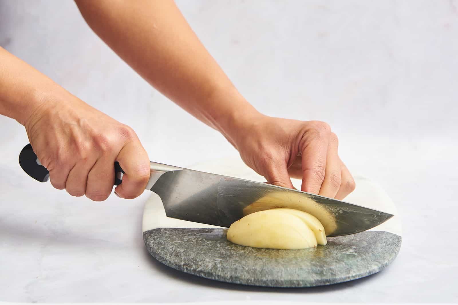A peeled potato being cut into slices.