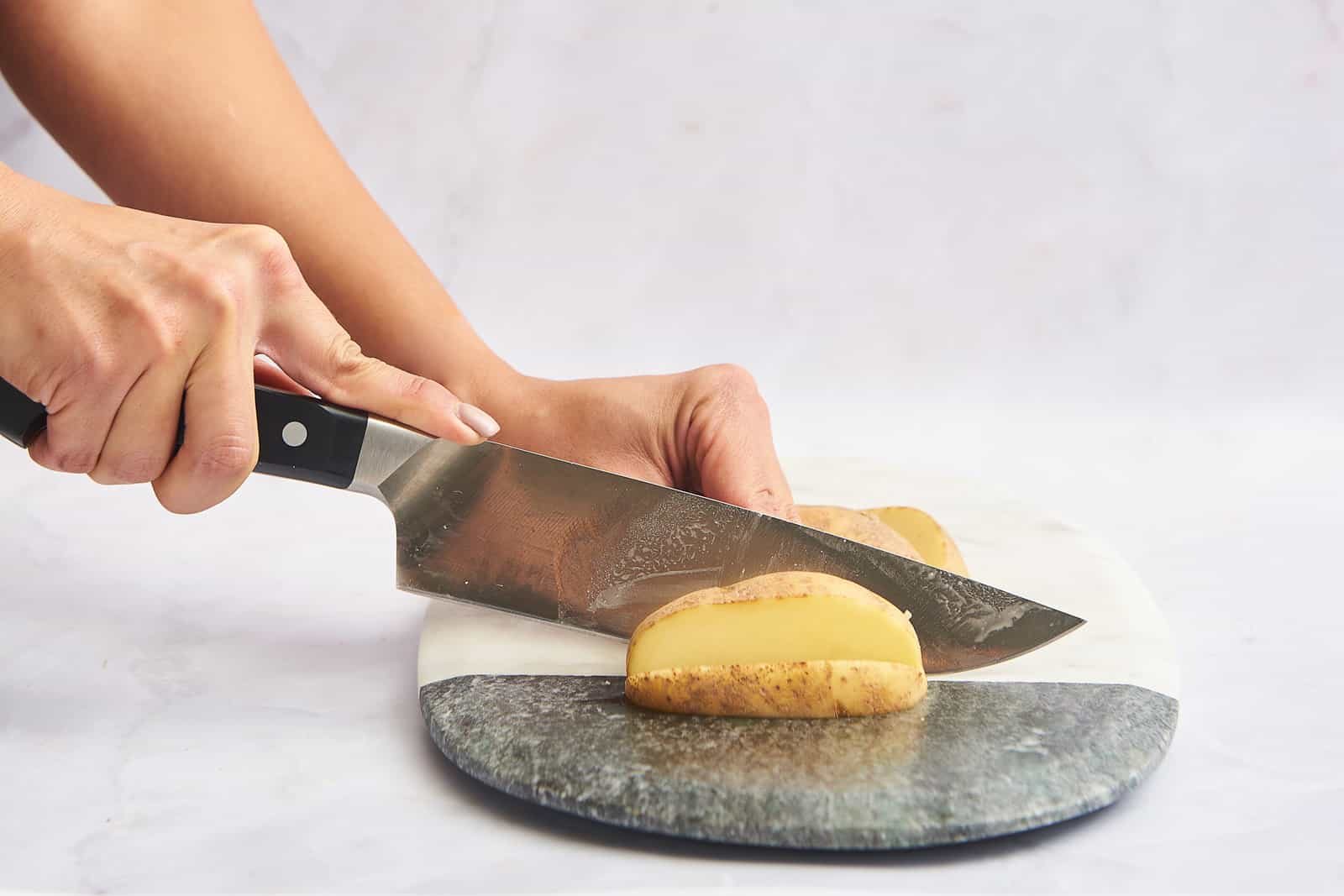 A potato being cut into slices.