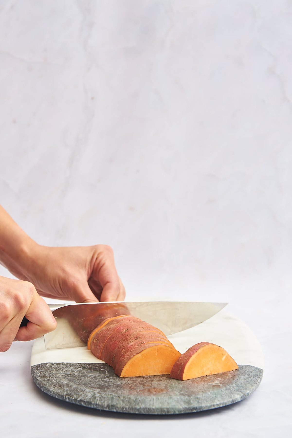 A sweet potato being sliced into wedges.