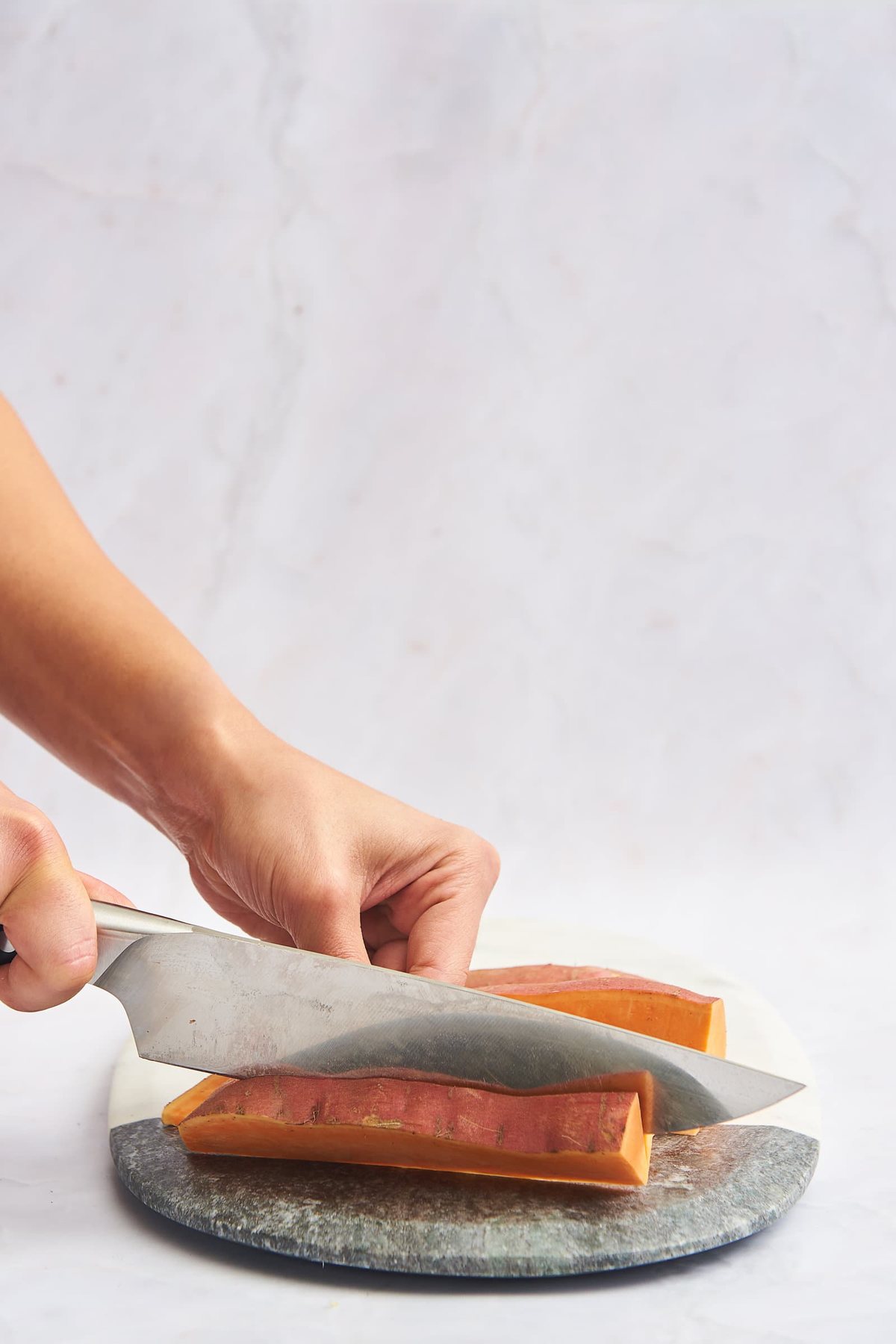 A sweet potato being sliced into sticks.