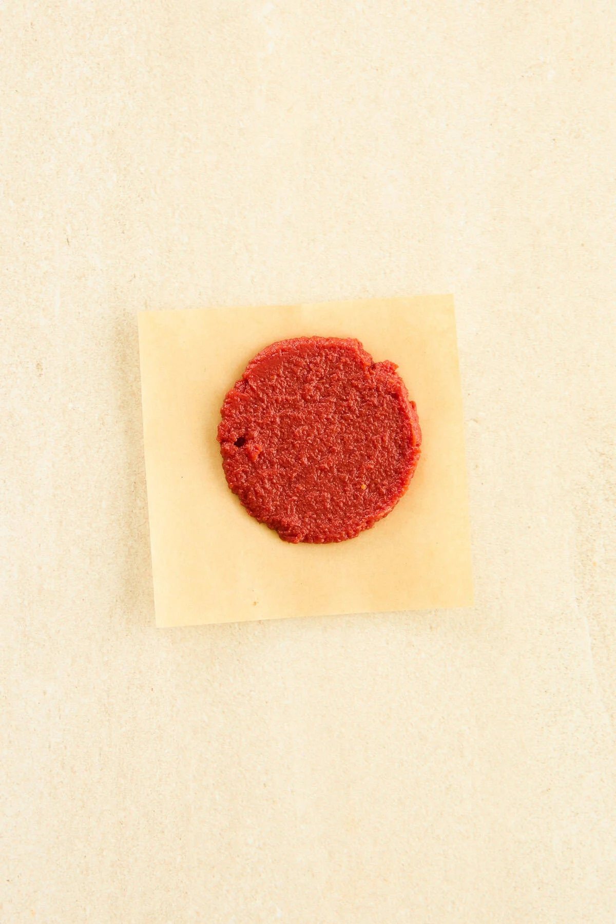 A disc of tomato paste on a piece of parchment paper.
