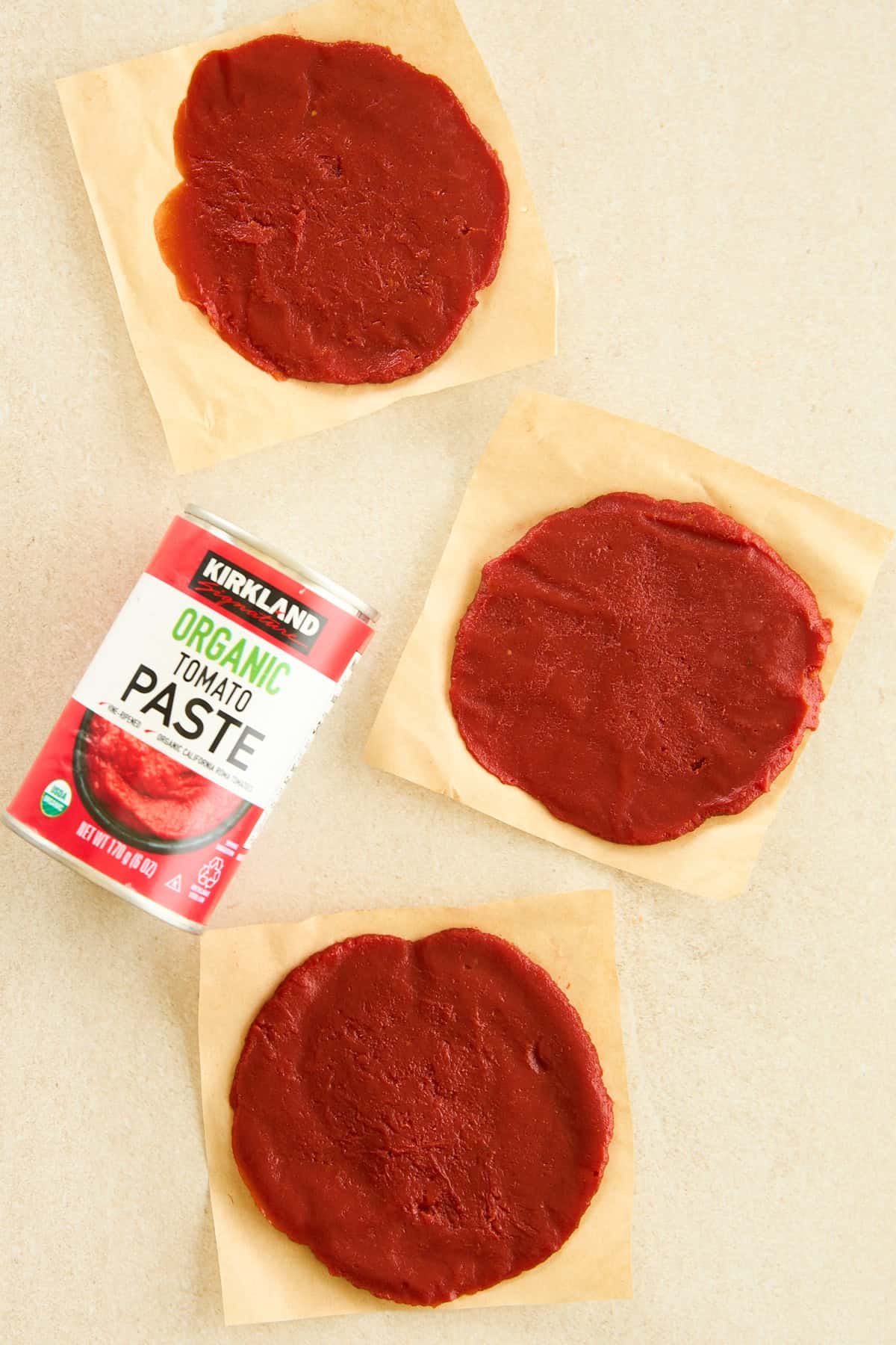 Frozen tomato paste discs on parchment paper next to a can.