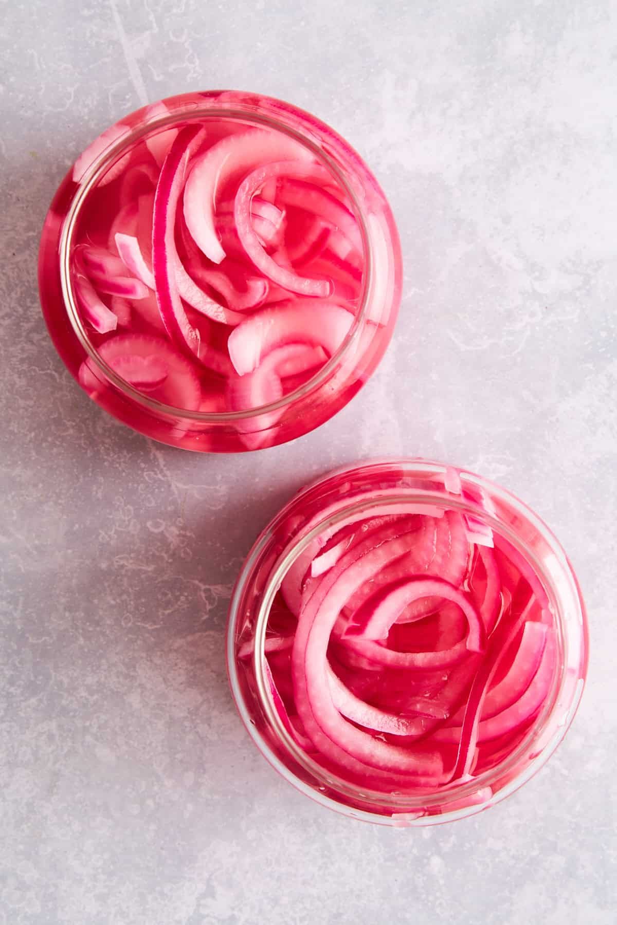 Overhead image of two jars of pickled red onions.
